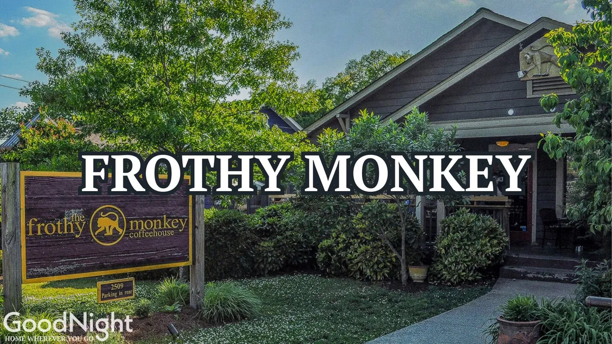 The image showcases the entrance of Frothy Monkey, a popular local coffee shop, surrounded by greenery. The welcoming facade and visible signage create an inviting atmosphere, and the setting highlights a vibrant community hub ideal for remote work or casual meetups.