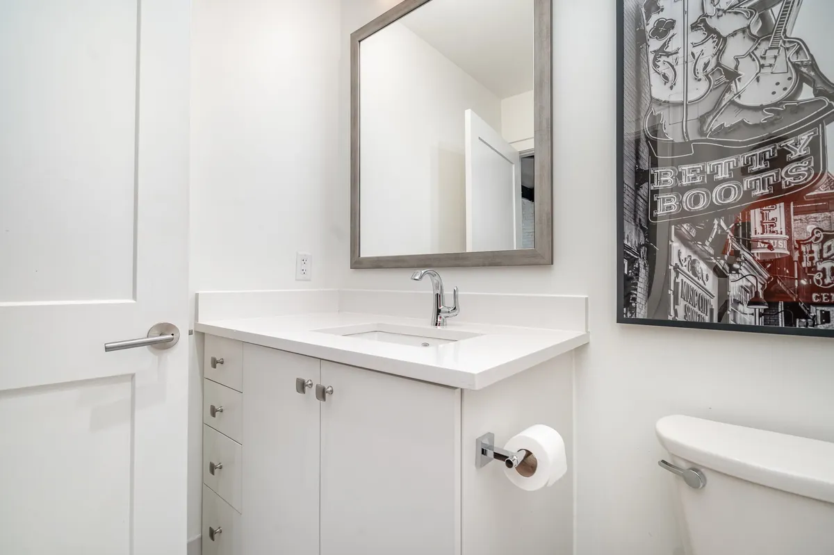 A compact half bath with a stylish sink, mirror, and decorative artwork. The fresh, inviting atmosphere makes it ideal for a quick refresh or last-minute touch-ups before heading out.